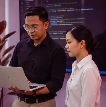 Two KDCI AI engineers reviewing code on a laptop
